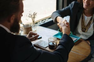 Two people shaking hands over a business meeting