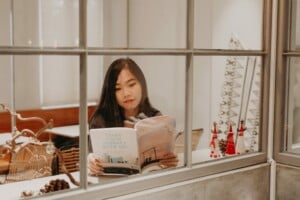 Woman reading magazine at window