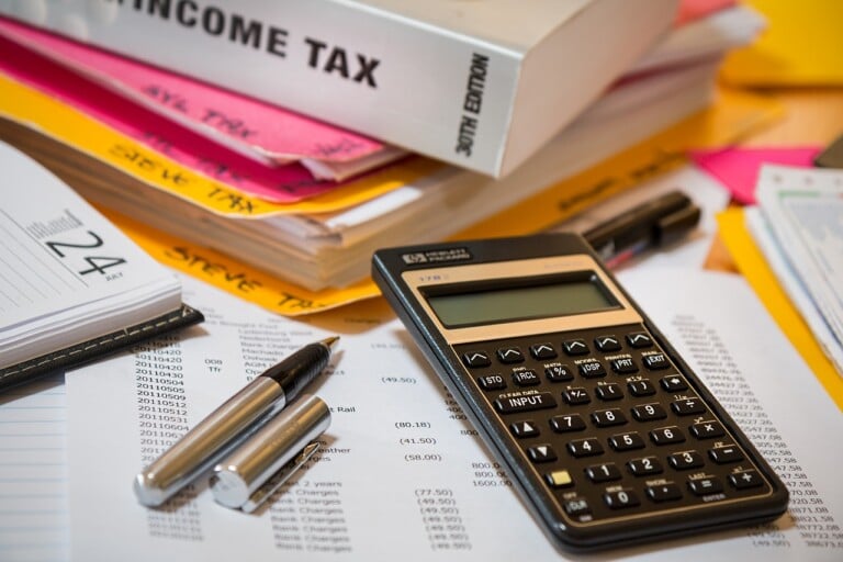 Income tax book sitting on folder with calculator and pen
