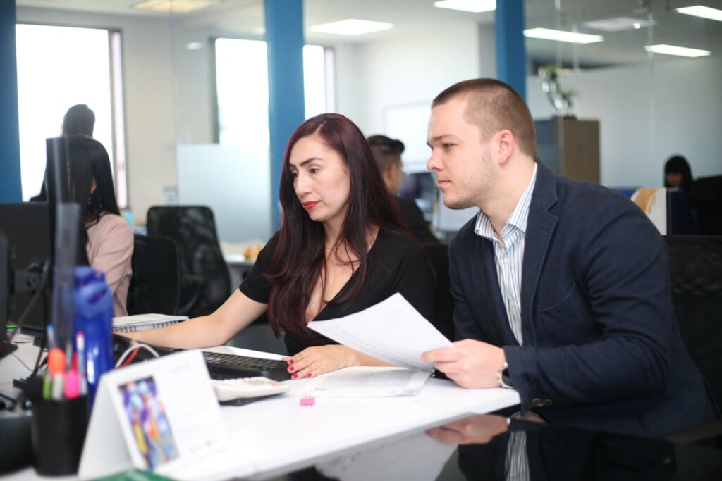 Two employees discussing at a table with papers.