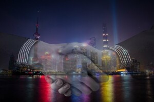Image of shaking hands superimposed on top of a city at night