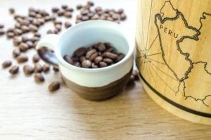 Cup of coffee beans next to map of Peru