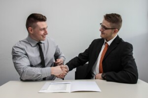Dos personas apretando manos mientras firman acuerdo de empleador de registro en Perú