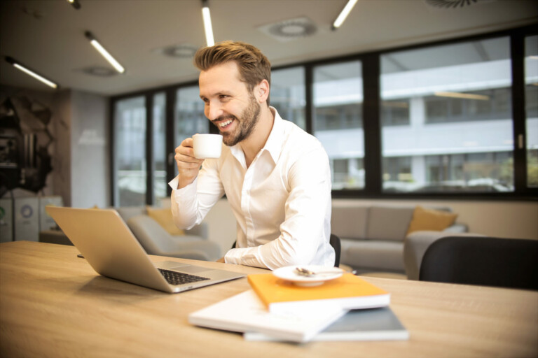 A man sitting at a desk drinking coffee
