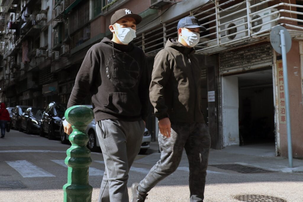 Two men with masks walking in the street, representing two employees of a El Salvador tech company