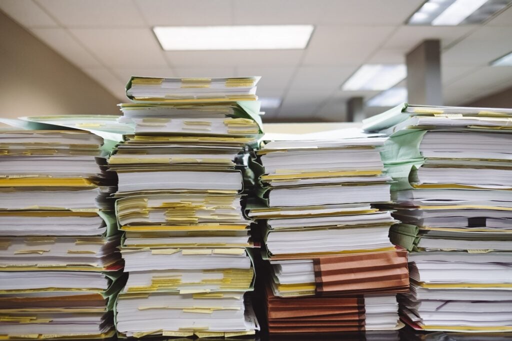 Uma pilha de papelada representando a grande quantidade de registros necessários para um exame de saúde da entidade no Uruguai
