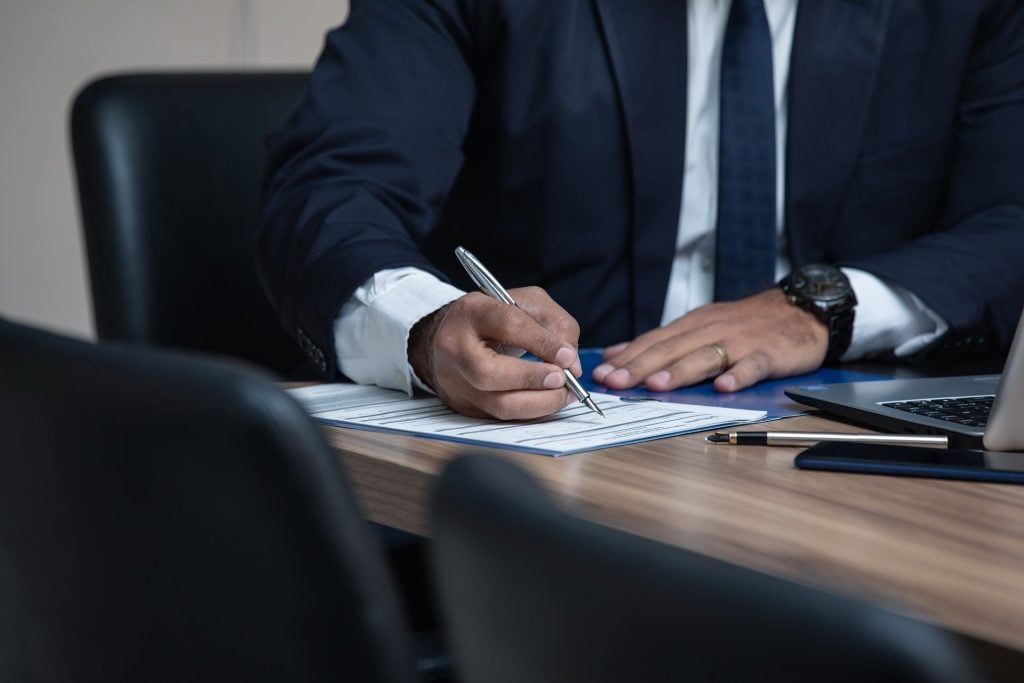 A man signing a document, representing a man outsourcing back office services in El Salvador.