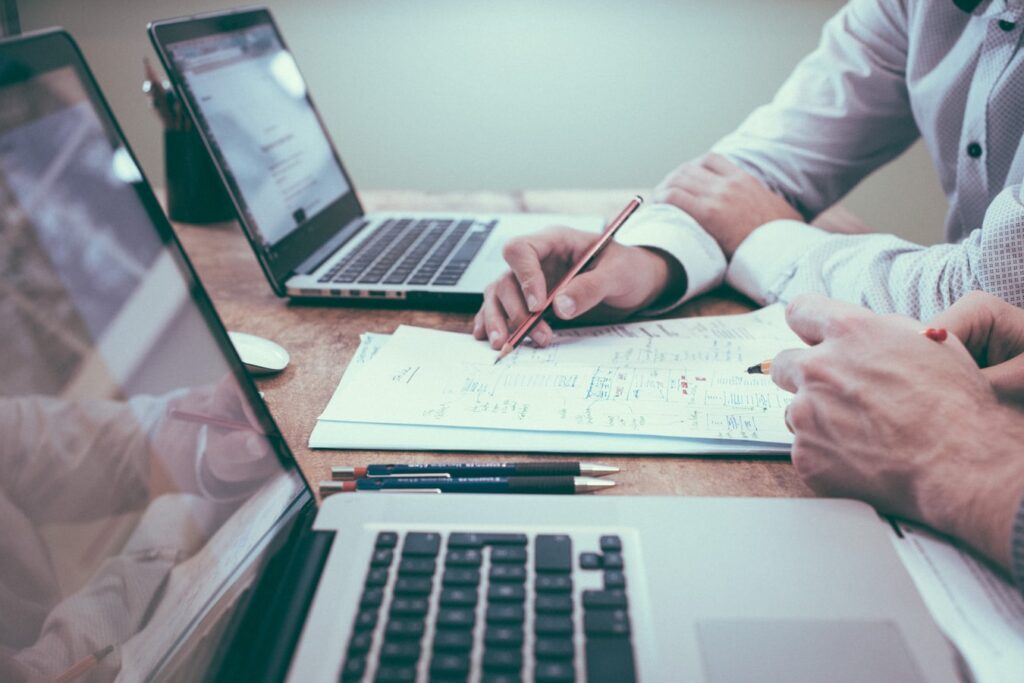 Dos hombres escribiendo en un documento, representando a dos personas realizando una revisión de cumplimiento corporativo en Costa Rica