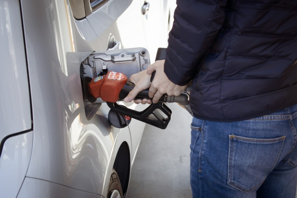 A photo of someone pumping gas into a car. Gasoline prices range around the region, as does affordability.