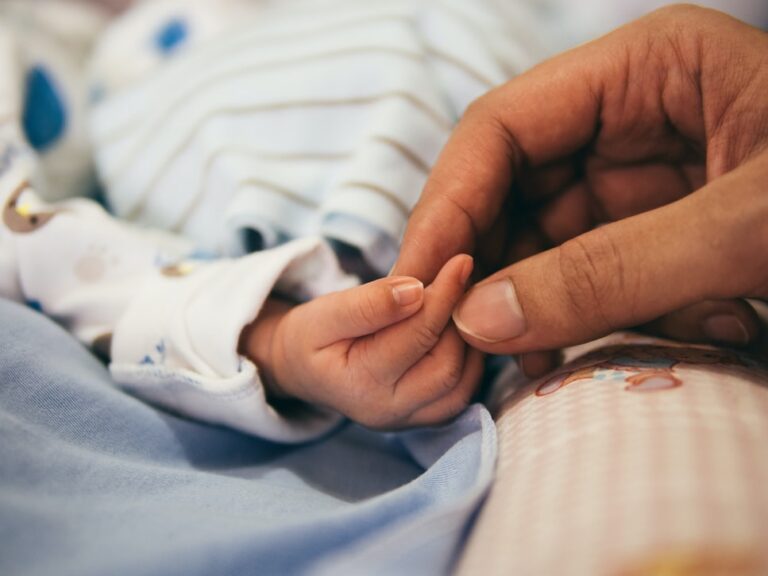 Una foto de un padre sosteniendo la mano de un bebé, resaltando las disposiciones de la licencia de maternidad en la ley de empleo en Colombia.