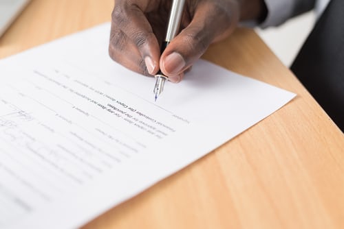 Imagen de archivo de una persona firmando un documento, que representa uno de los cuatro tipos principales de contrato en la legislación laboral de Brasil