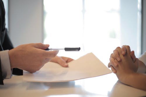 A stock photo of a someone being passed a document to sign, representing one of the two main contract types under employment law in Bolivia