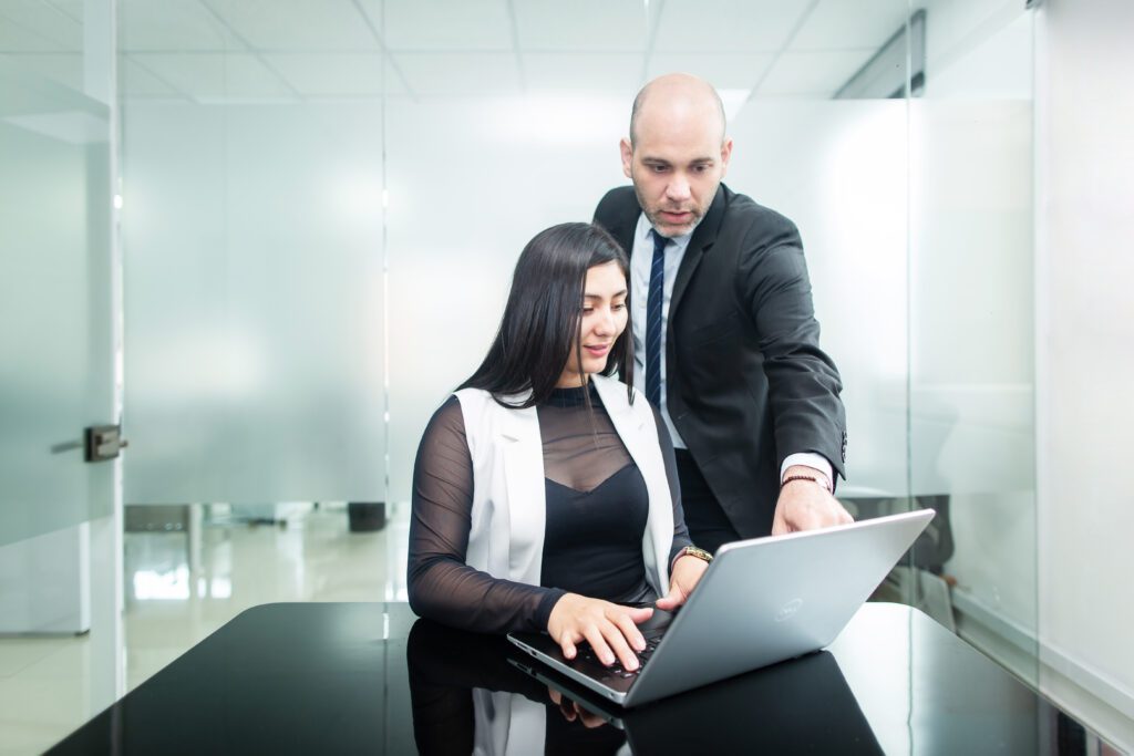 Un hombre y una mujer en una oficina mirando una computadora, que representan a dos personas que buscan información sobre la formación de una empresa en Guyana.