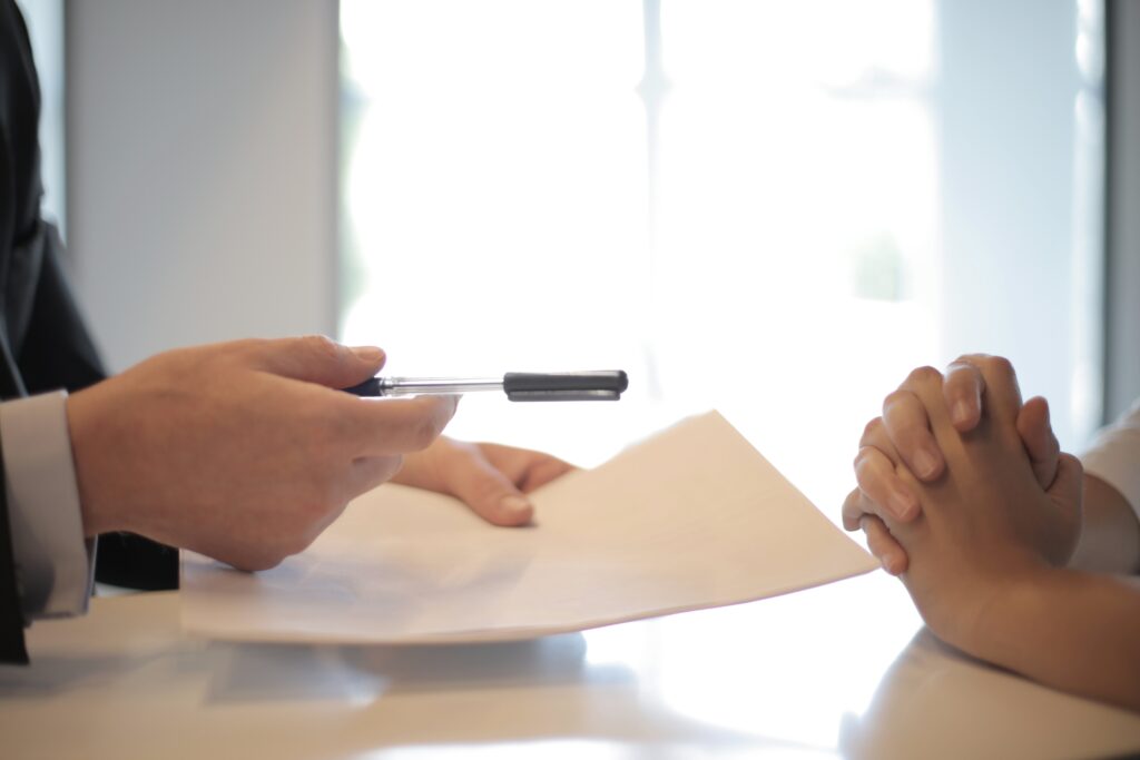 Uma imagem de estoque de alguém recebendo um documento para assinar, representando um dos três principais tipos de contrato sob a lei trabalhista no México