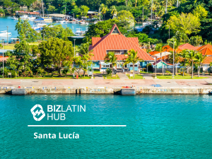 Uma cena costeira colorida com um edifício de telhado vermelho proeminente com vegetação exuberante e uma marina ao fundo. A água em primeiro plano tem um tom vibrante de azul. A imagem inclui o texto “Bizlatin Hub - Santa Lucía”, destacando a formação de empresas em Santa Lúcia.